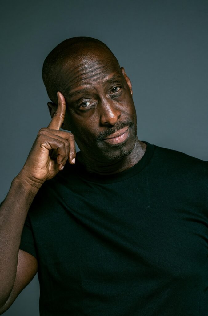 pexels-photo-4584378-4584378 A close-up portrait of a thoughtful black man in a dark shirt, touching his temple.